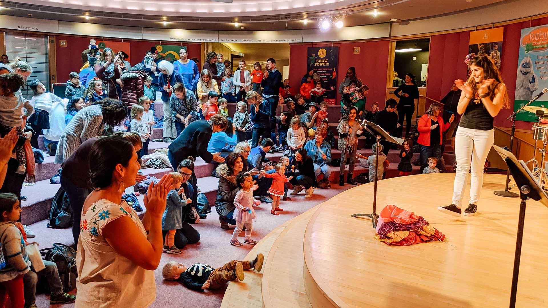 A performance of Kids in the Rotunda. Many parents and children watching a show. Many of them are standing and dancing.
