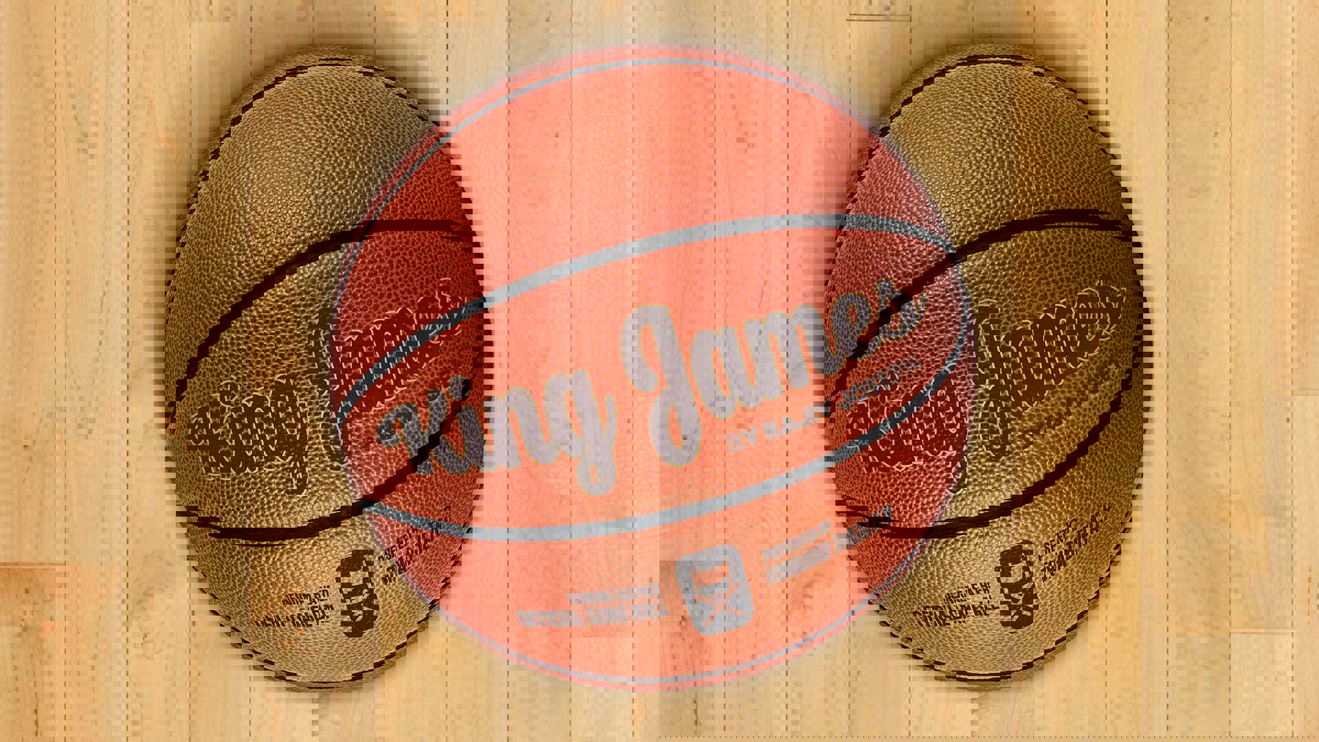 A basketball on a light wood floor that reads "King James by Rajiv Joseph" in a scripted font that displays like a basketball logo.