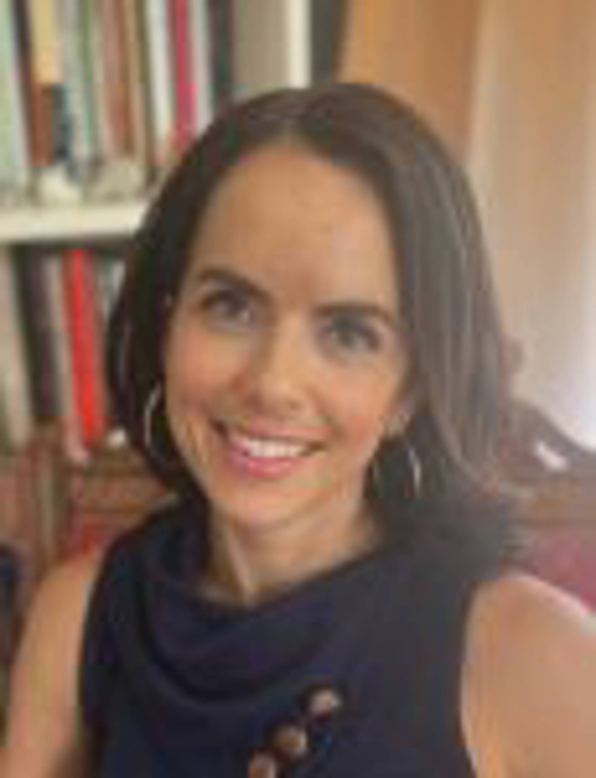 Headshot of a caucasian woman with long brown hair and a dark top.