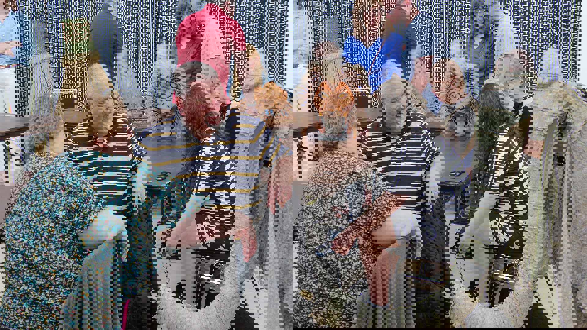 Two people sit and look towards an elephant puppet made out of paper.