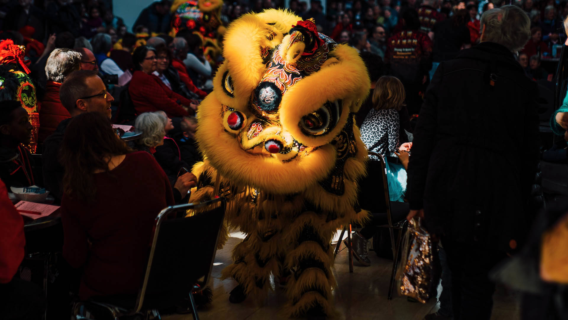 A yellow Chinese dragon walking among a crowd.