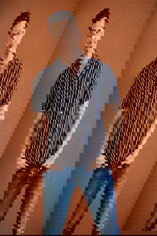 Headshot of Ryan Silverman. He has a handsome youthful face with short brown hair and brown eyes. He is wearing a striped short sleeve button up.