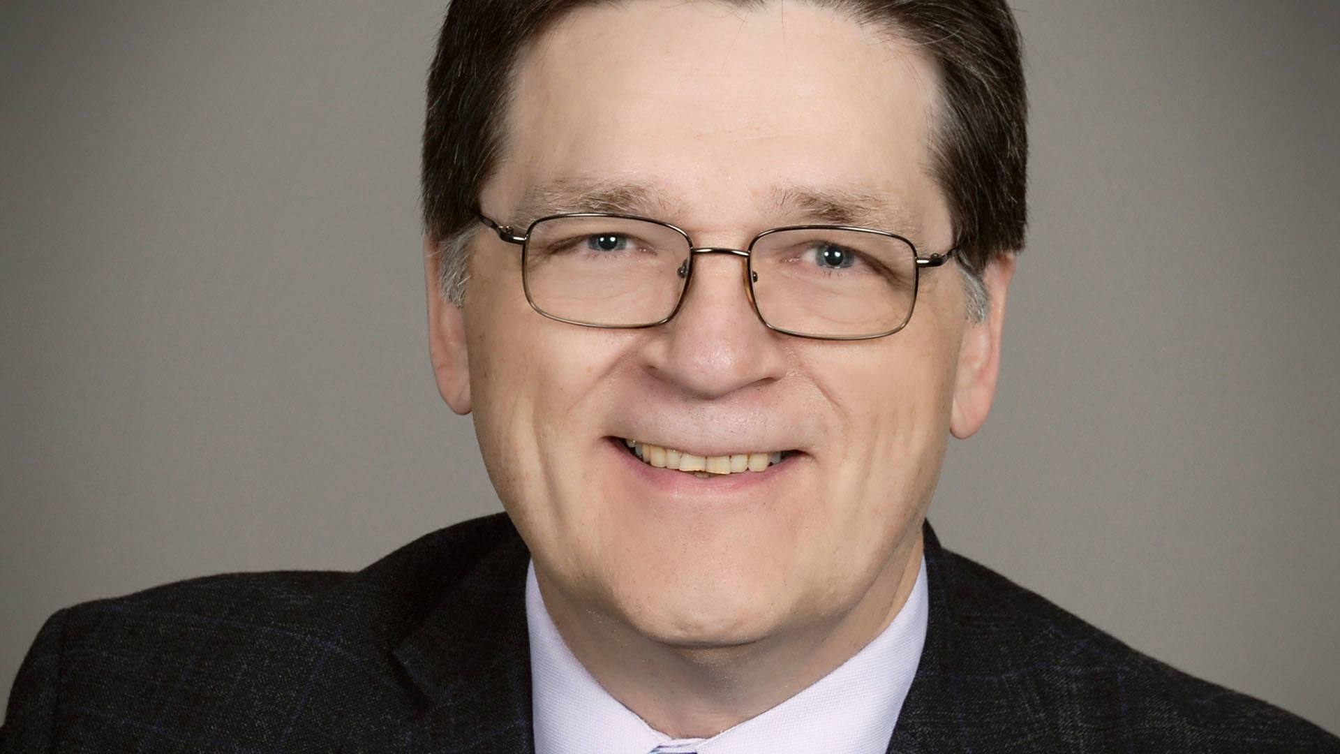 Headshot of a middleaged white man with dark hair and glasses.