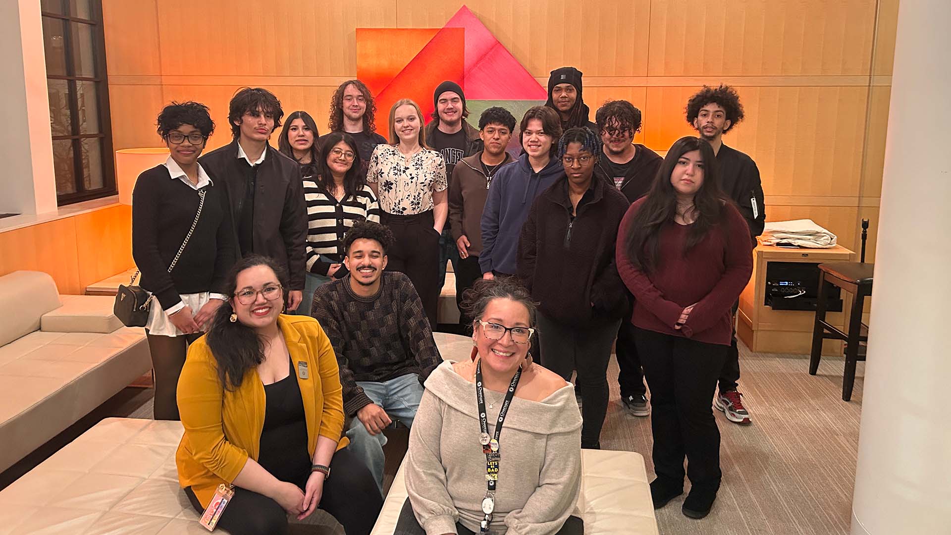 A group of "Hamilton" cast members, Overture staff, and Cue 608 youth artists pose for a photo in a Promenade Lobby.