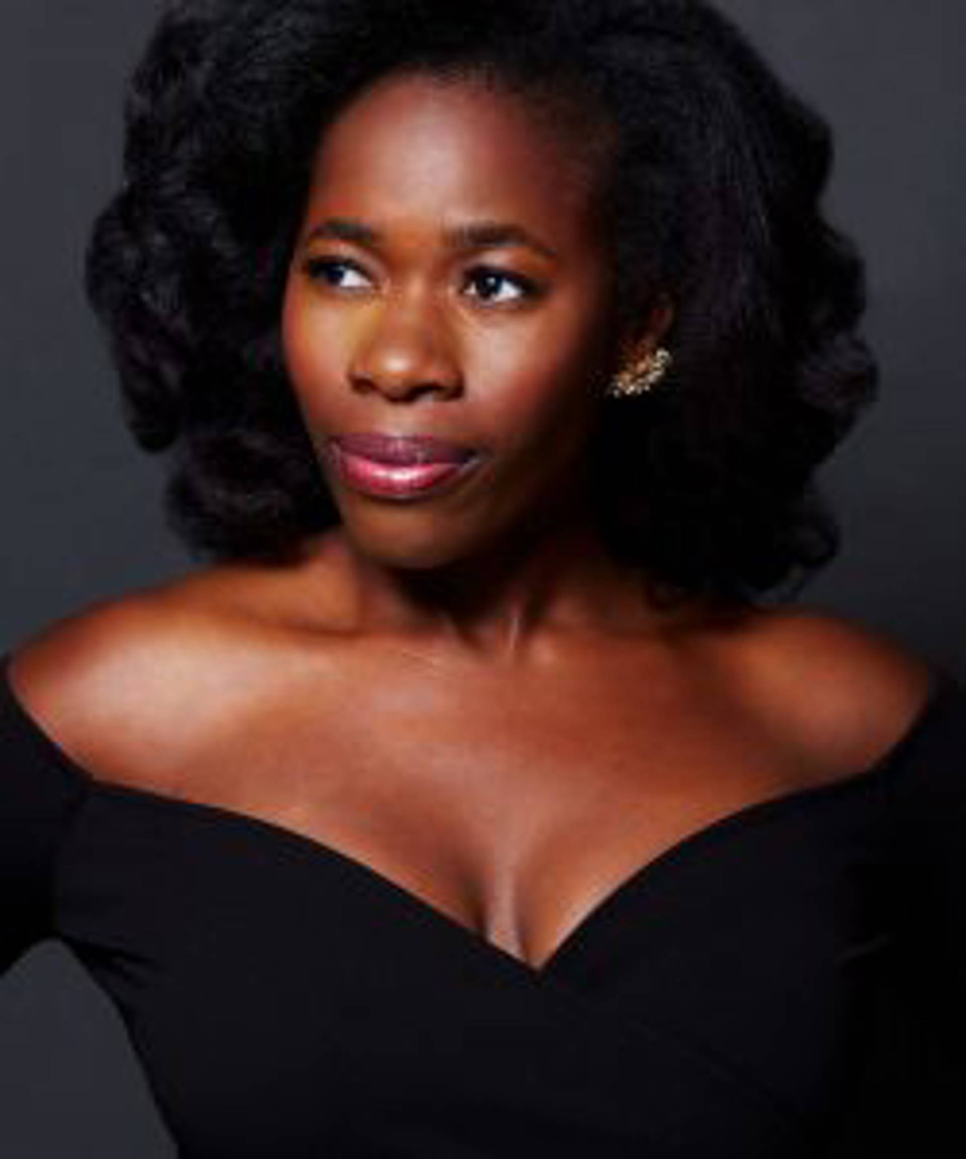 Headshot of an African American Woman with brown eyes and medium hair in a black dress.