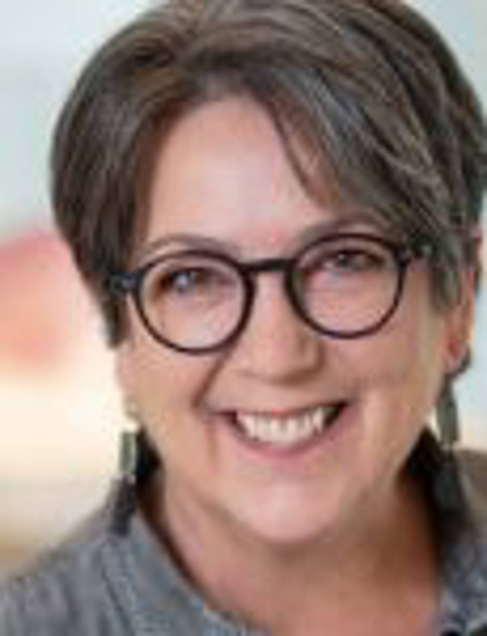 Headshot of a middle aged woman with light complexion, medium brown hair and glasses.