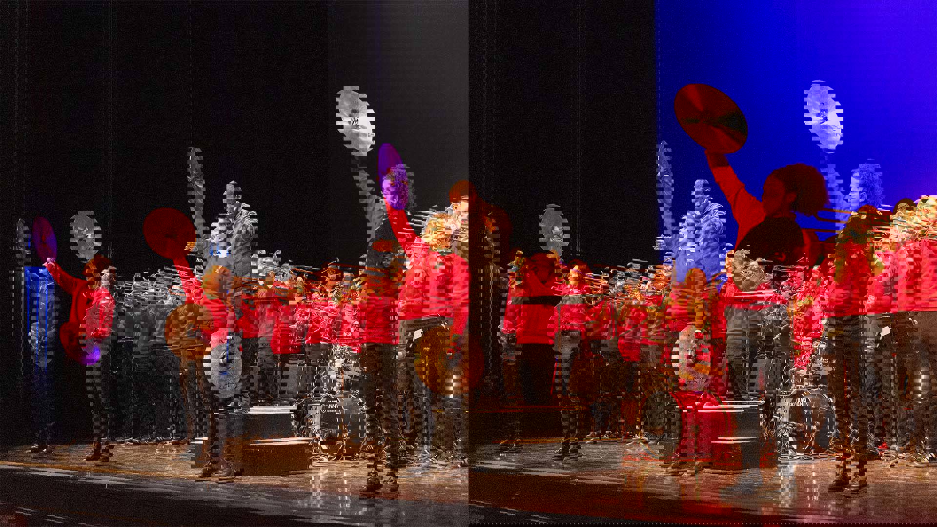 The UW Marching Band performing on Overture Hall stage. Four cymbal players stand at the front.