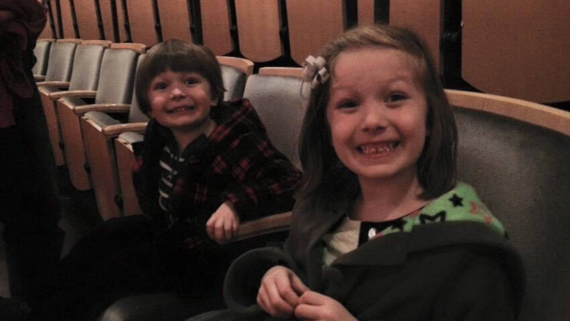 Two young kids smile for a portrait in Overture Hall. They both have dark eyes and brown hair.