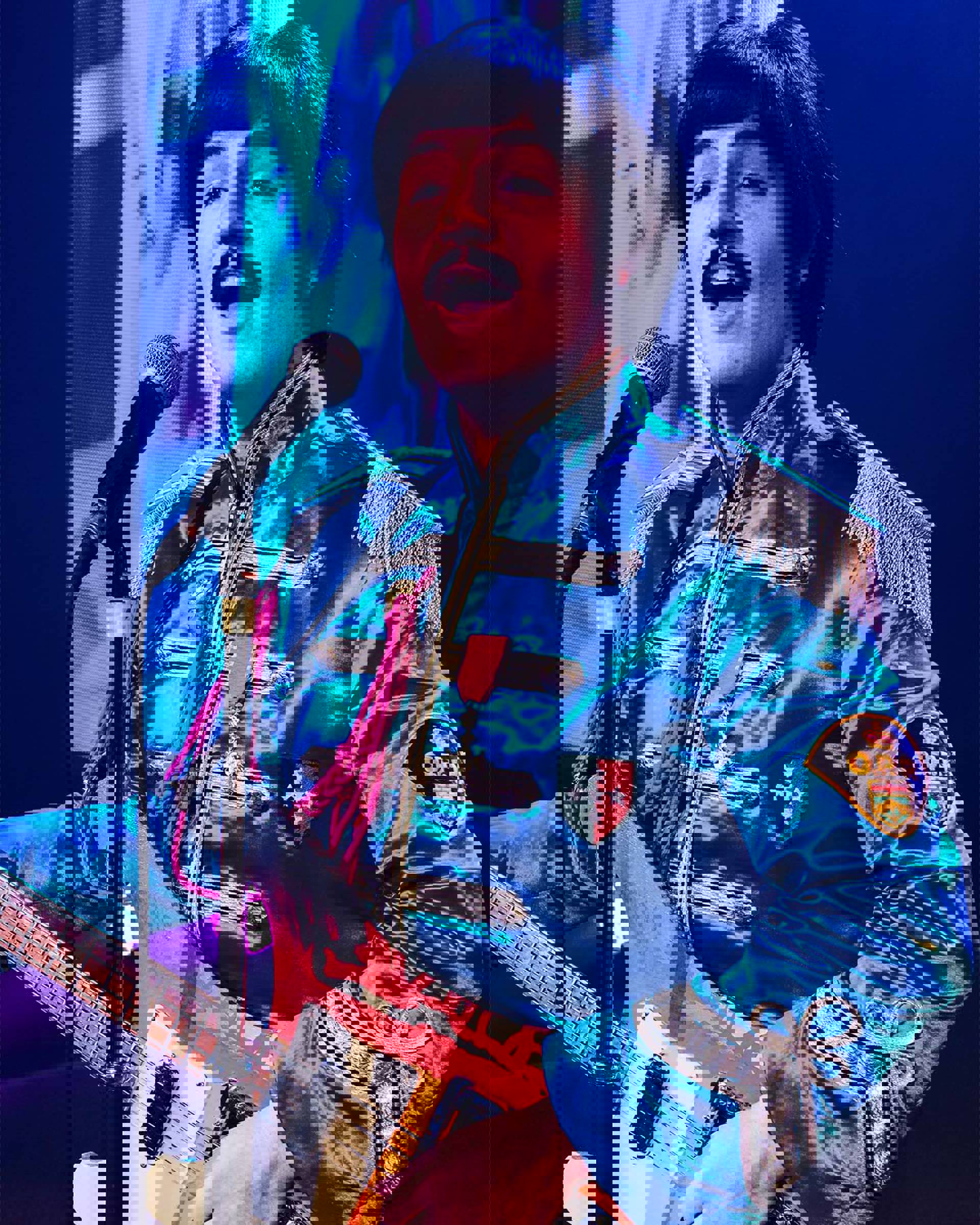 A Paul McCartney impersonator wearing a blue Seargent Peppers outfit and holding a guitar. He has dark hair and a moustache