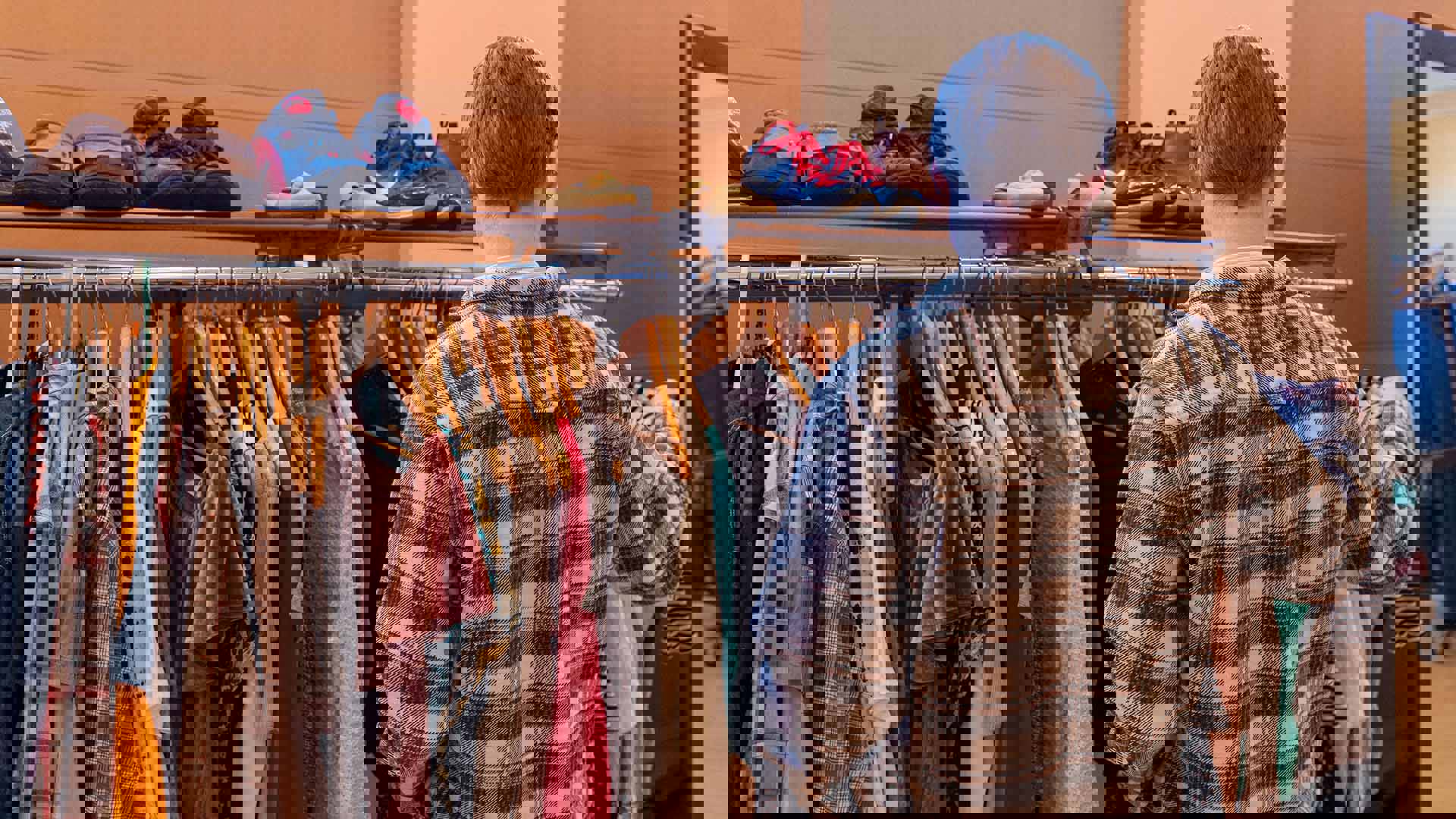 A standing rack filled with clothing hung on wooden hangers, ranging in colors and fabric textures.