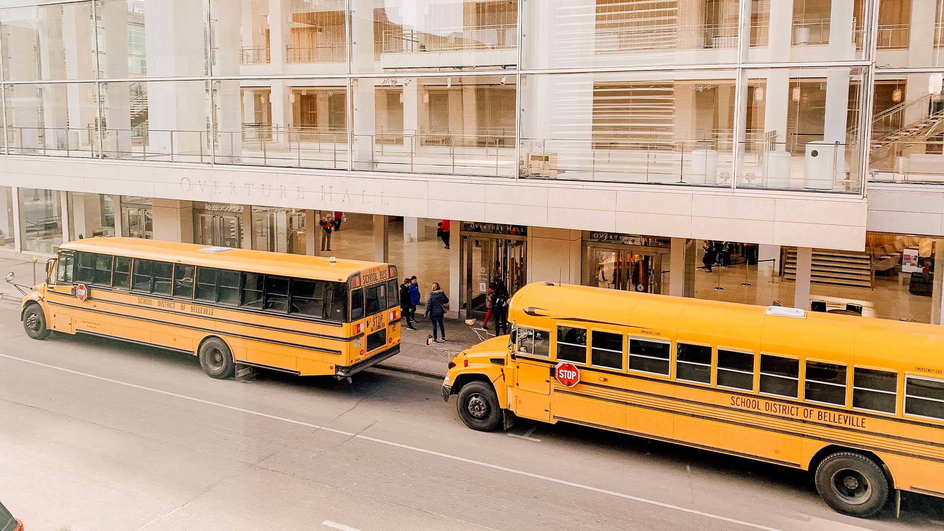 Two school buses parked outside of Overture Center.