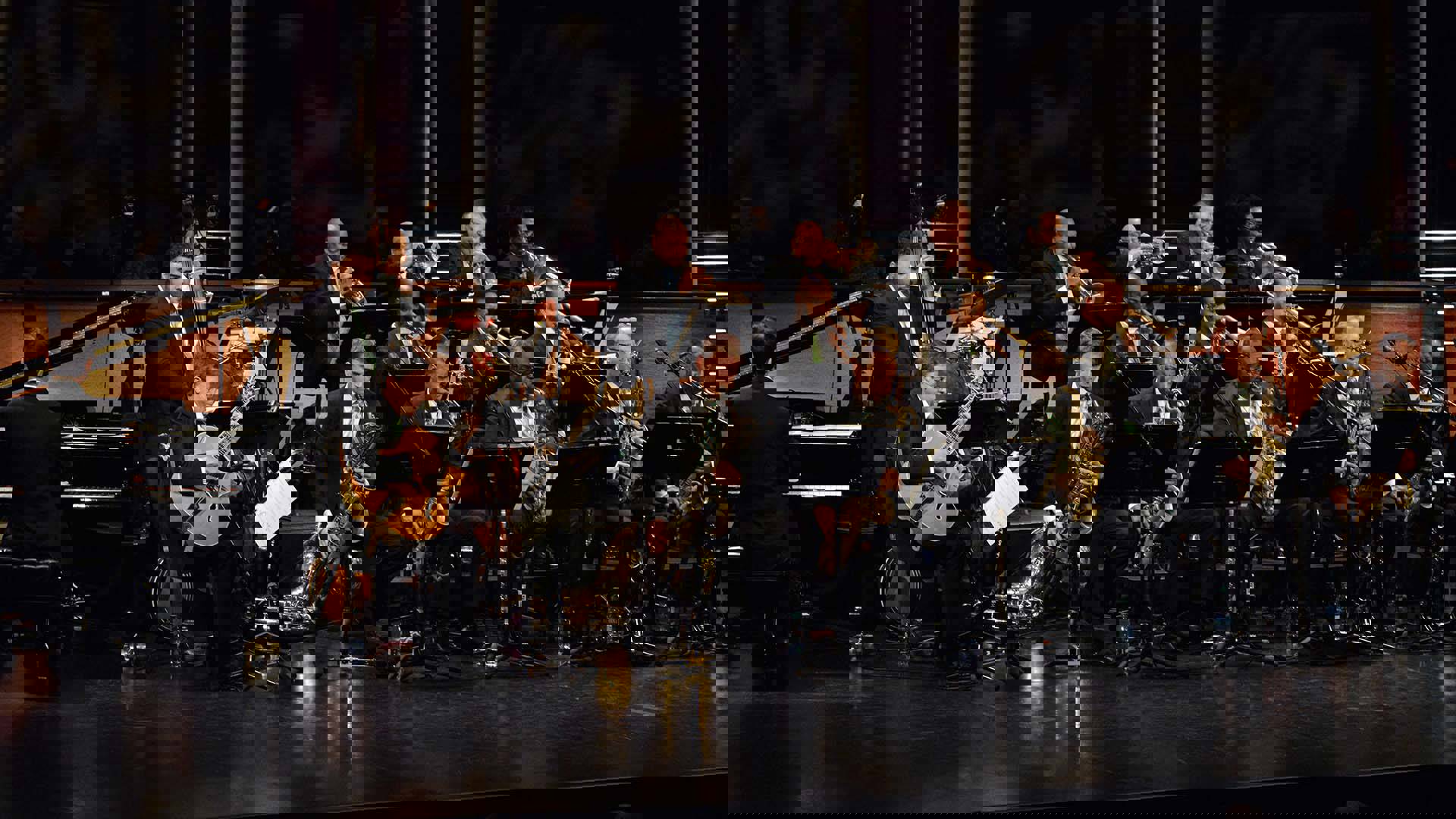 A Jazz big band performing on a stage. The members are wearing nice suits