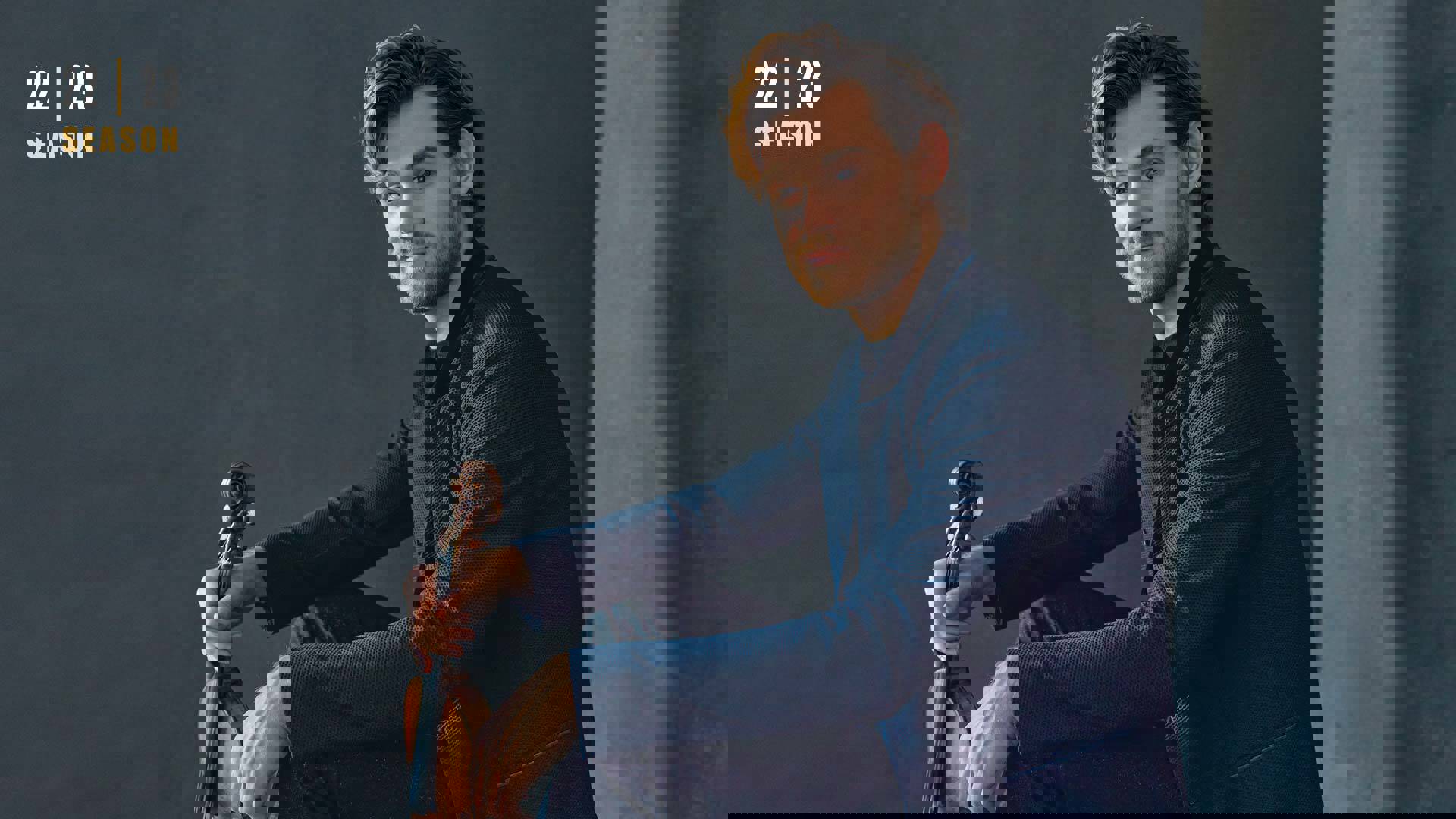 Banner text reads: 22 | 23 season. A man in a blue suit is sitting profile and holding a violin. His head is toward the viewer. He has wavy brown hair and a short beard.
