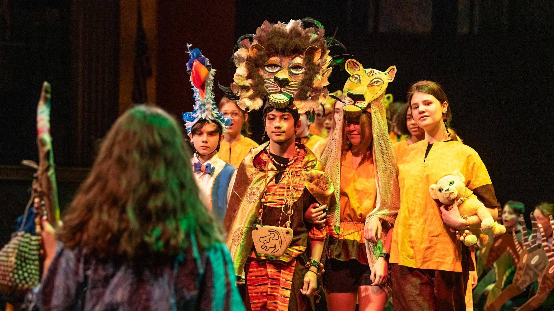Students dressed as lion and bird characters from The Lion King for a middle school musical performance.