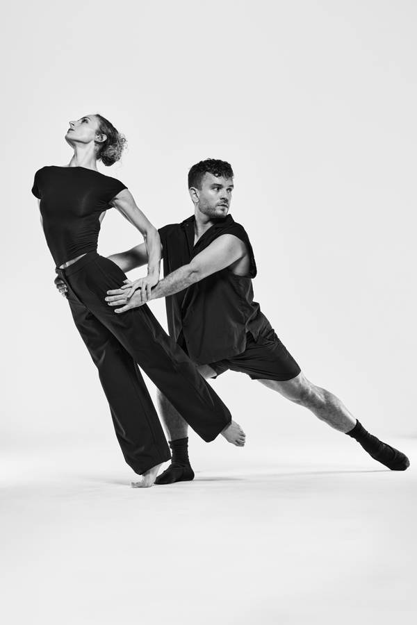Greyscael image of two dancers in black outfits.