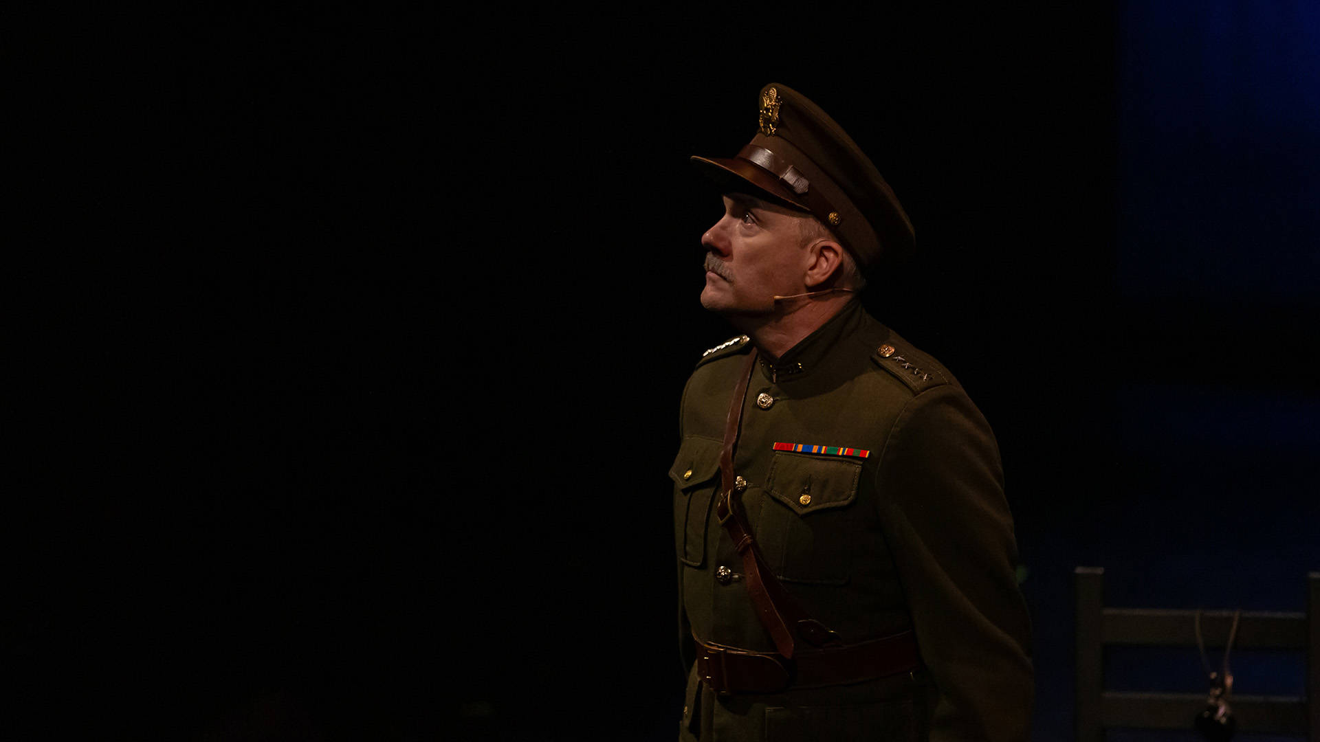 Man with light complexion and mustache wearing a military uniform looks into the distance.