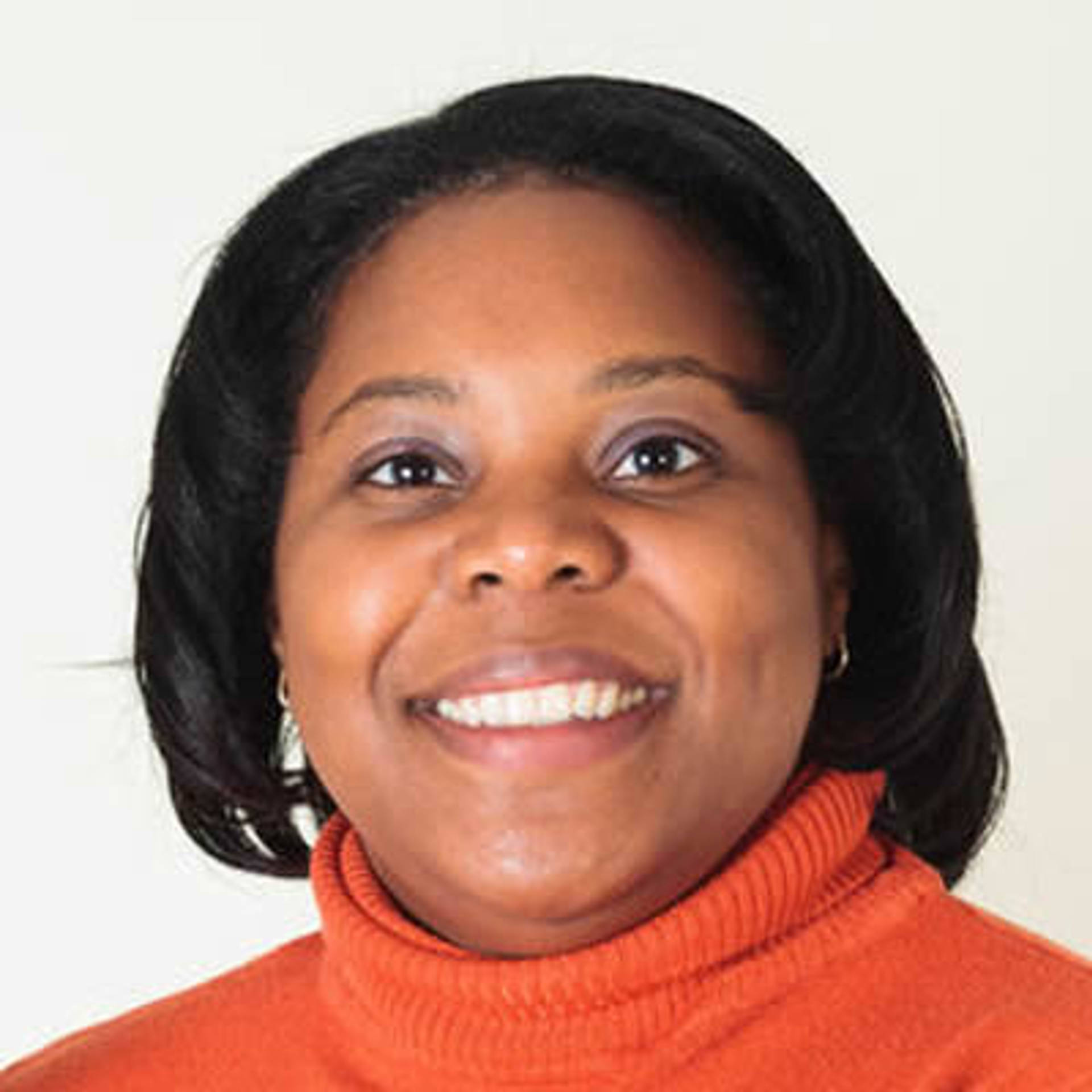 Headshot of an african american woman with medium length dark hair and dark eyes in an orange top.