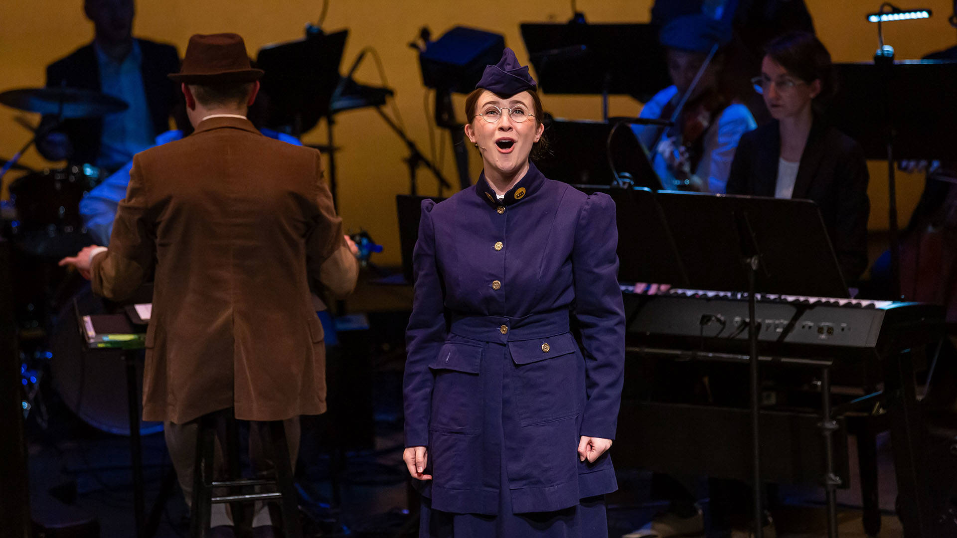 Woman with light complexion wearing blue military uniform sings during a performance of "The Hello Girls."