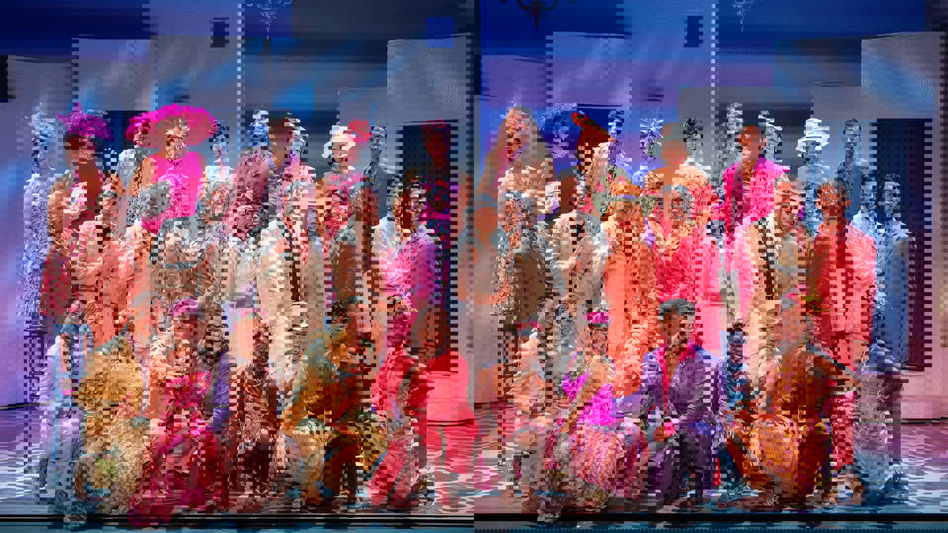 The Mamma Mia ensemble standing together in fancy cream and warm tone outfits.