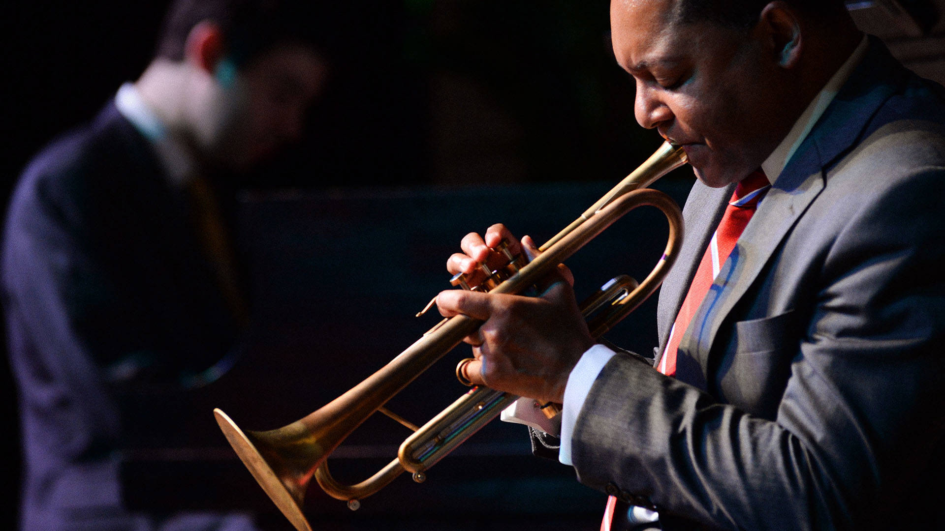 Wynton marsalis in profile view playing his trumpet.