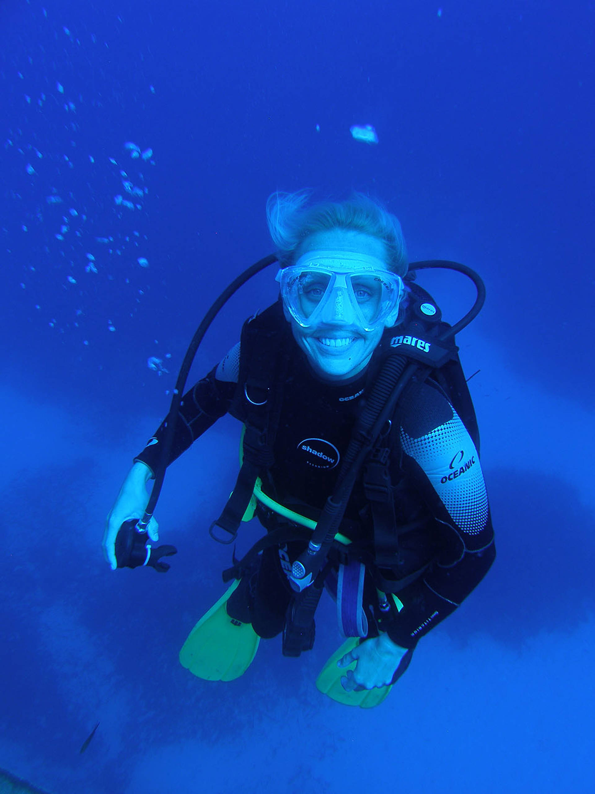 Lucy Hawkes underwater in scuba gear smiling towards the camera