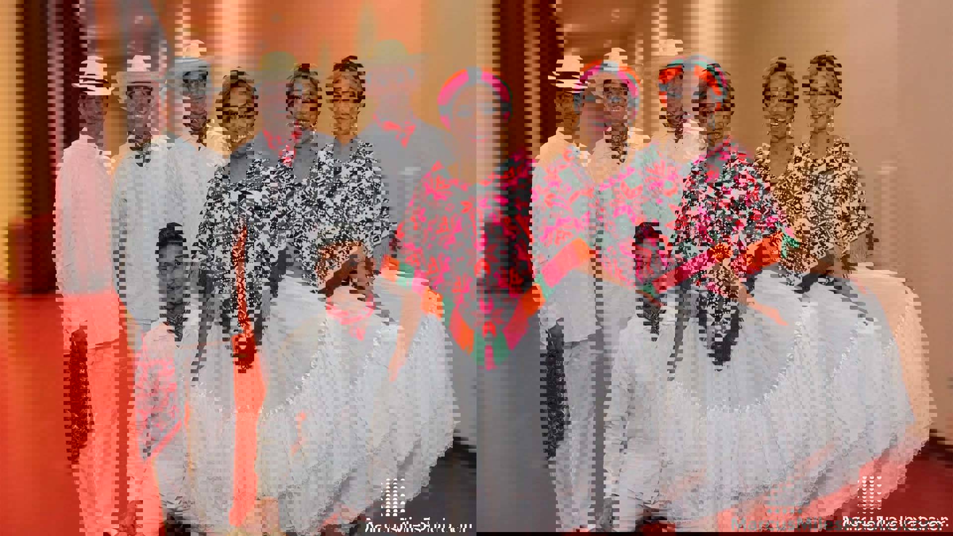 A group of performers from DanzTrad in traditional Mexican outfits - flowing white clothes, the women wearing colorful shawls and headwear and the men with colorful neck scarves and hats.