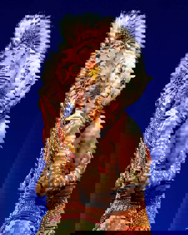 Two actors dressed as Simba and Nala embrace eachother and smile