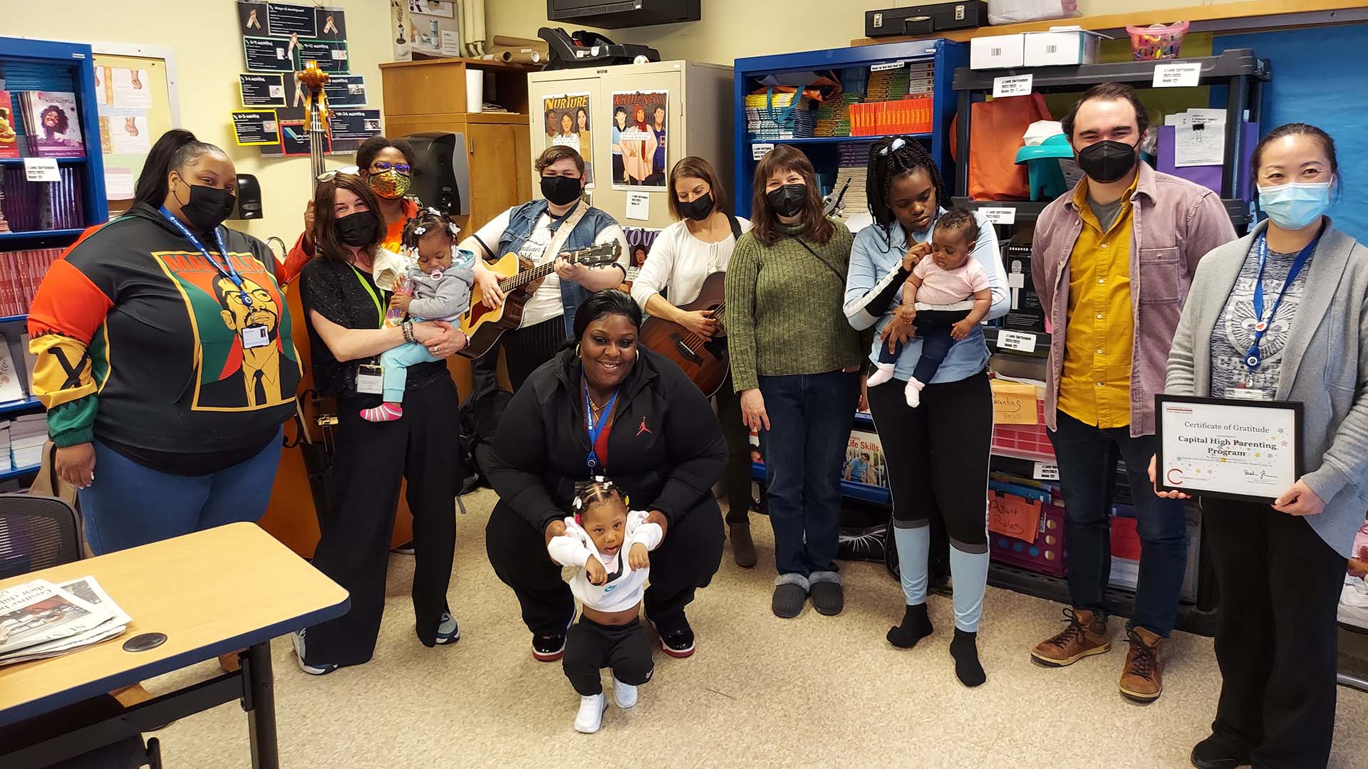 A group of people, some holding instruments, others holding small children, pose for a picture.