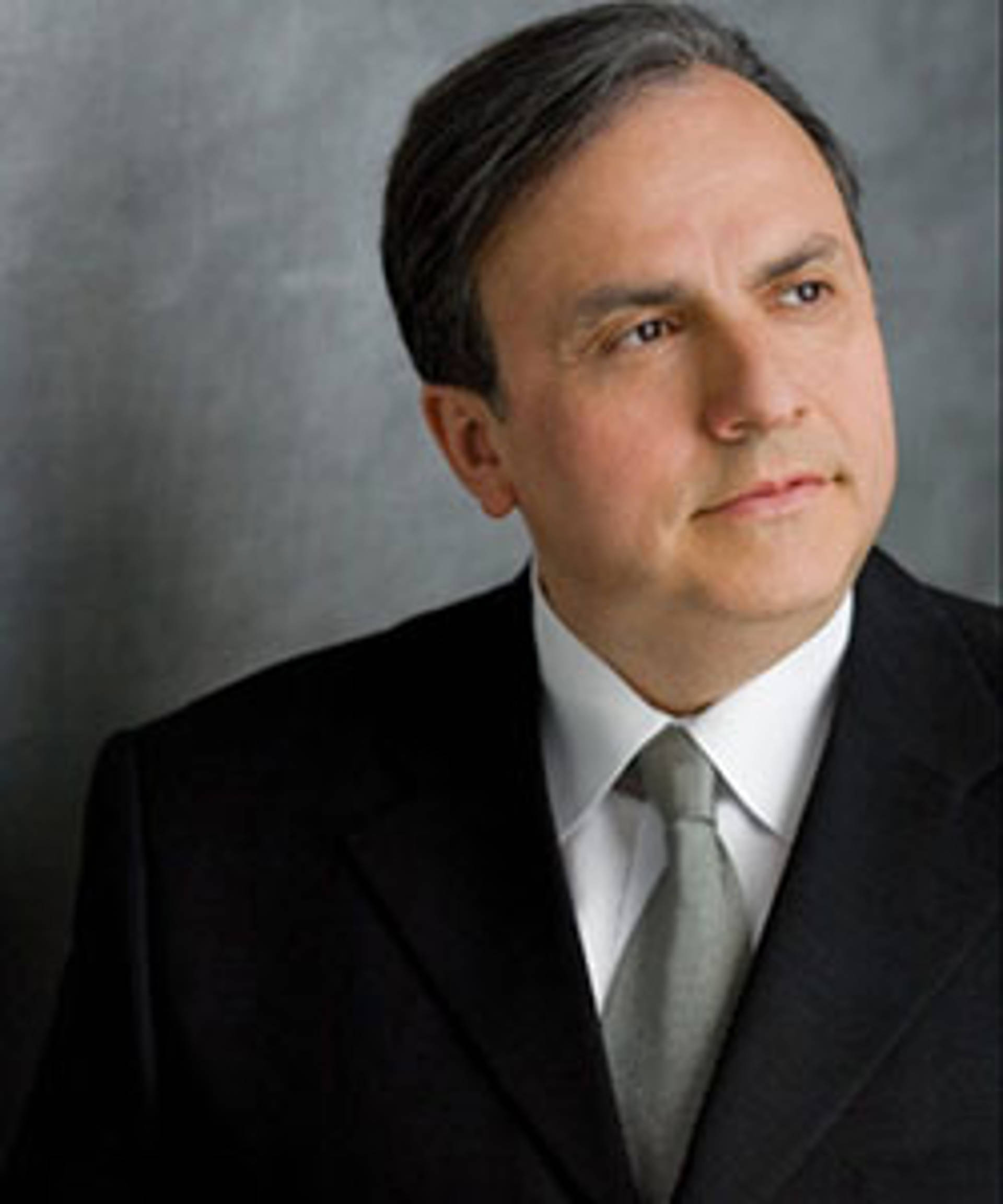 Headshot of a caucasian man with dark eyes and short brown hair in a suit
