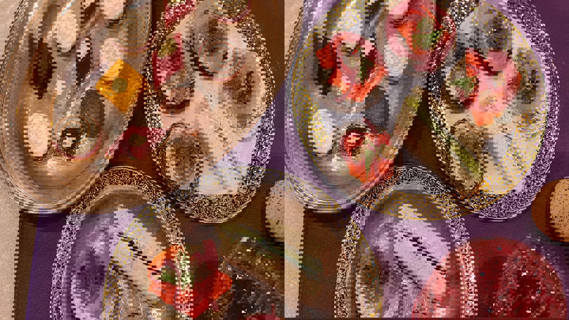 Aerial view of three plates of sandwiches and finger foods, alongside a glass of red punch.