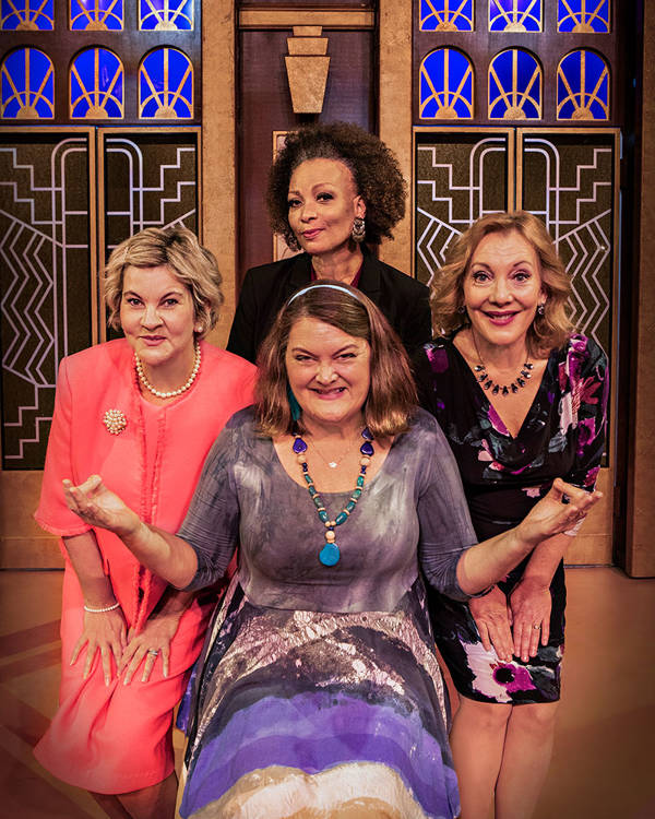 Four women make funny faces and pose together.