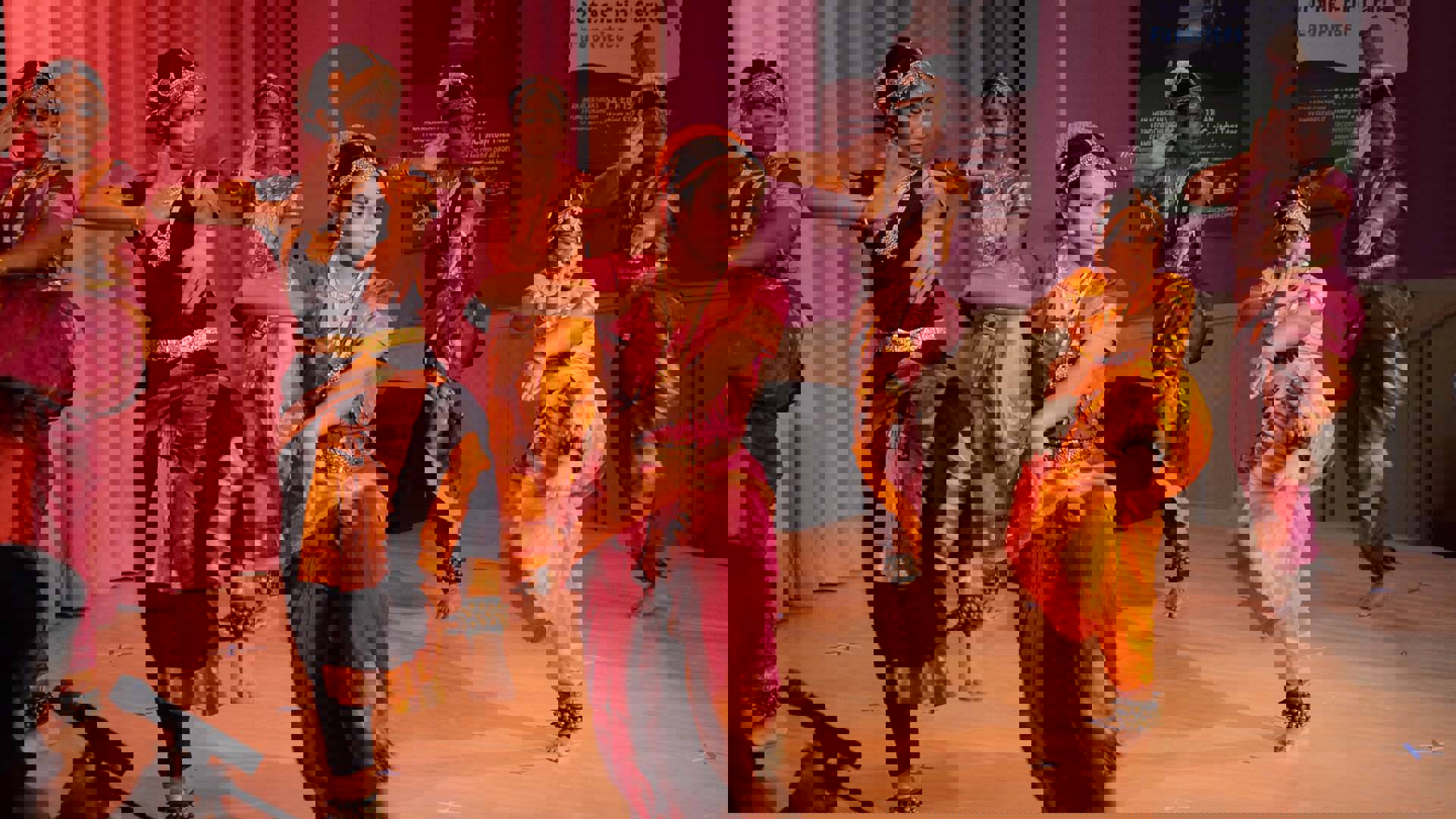 Six dancers performing on the Rotunda Stage wearing pink and yellow traditional Indian clothing and gold head ornaments.