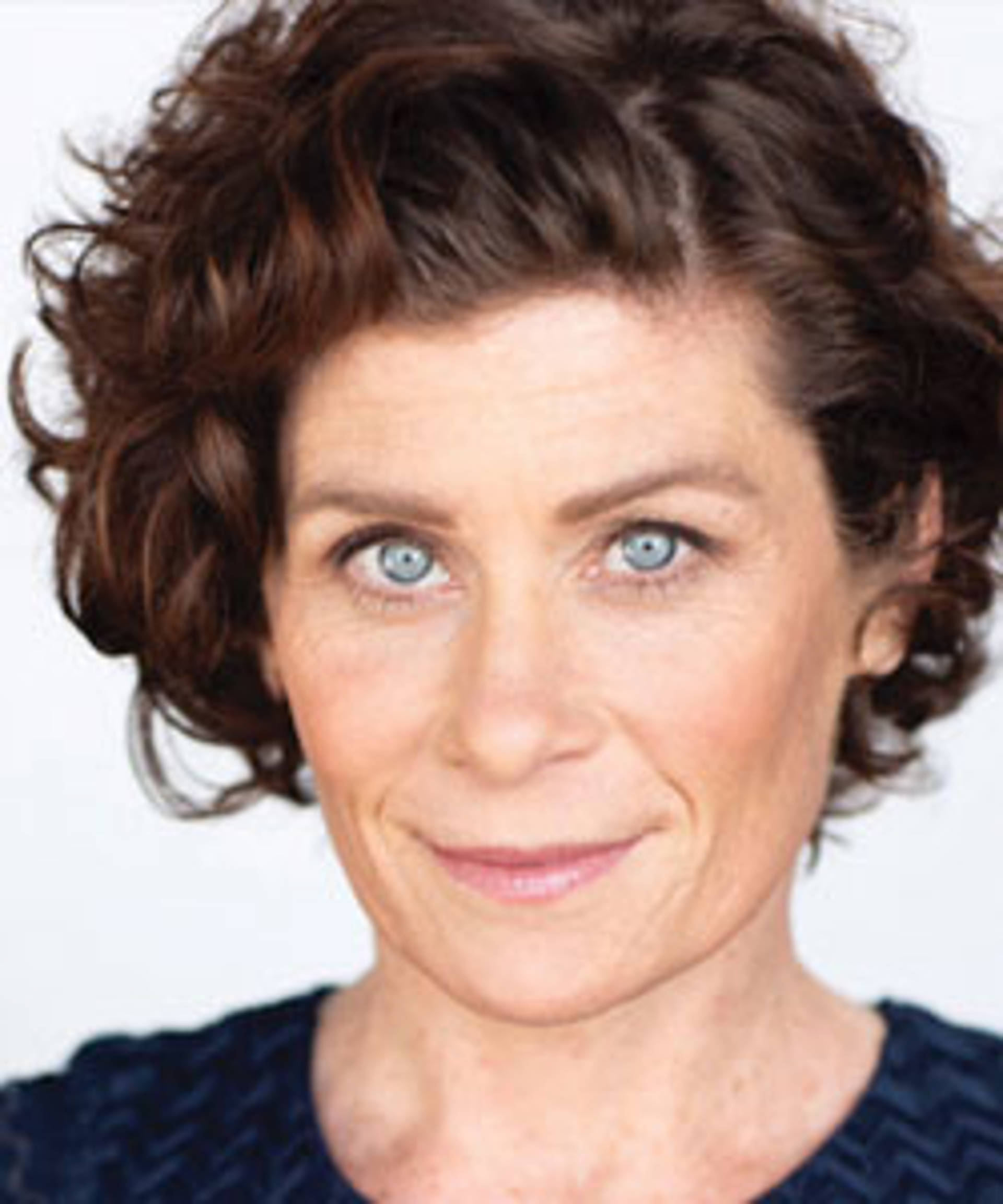 Headshot of a caucasian woman with icy blue eyes and wavy brown hair worn up