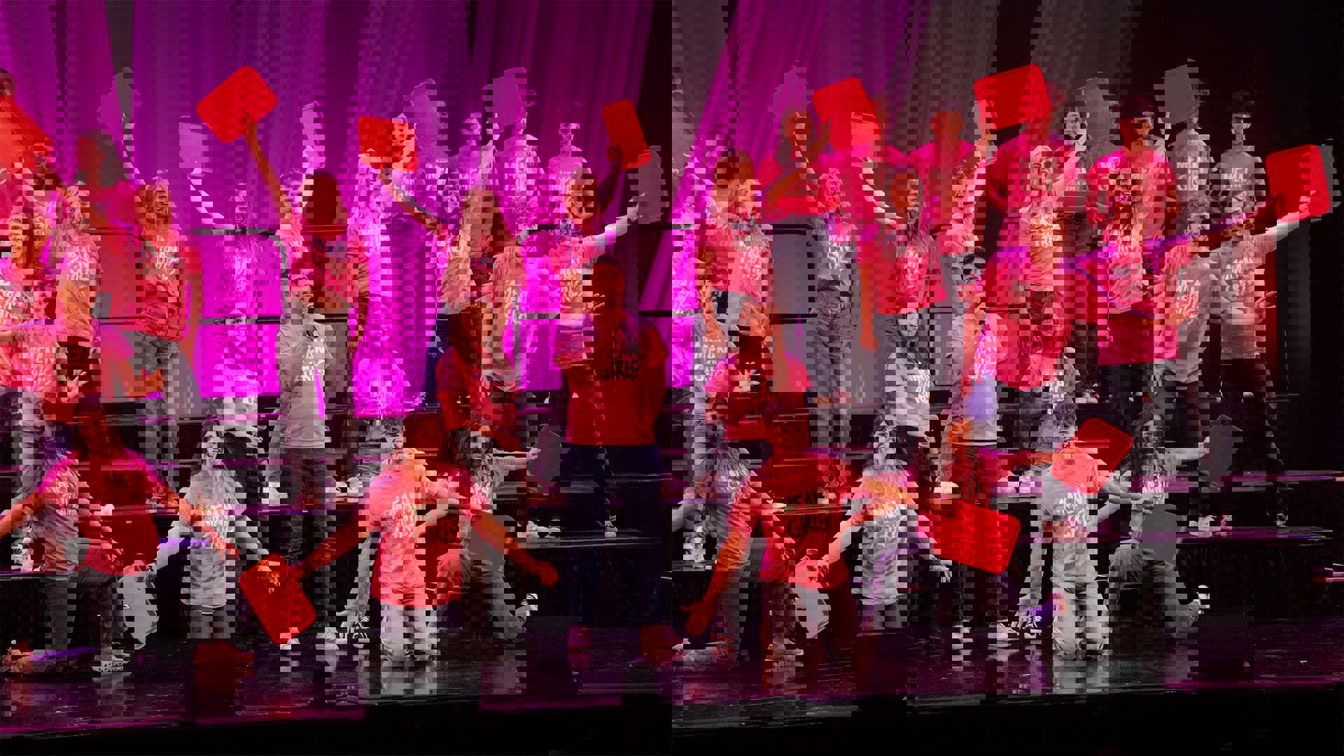 A student ensemble in matching Mean Girls pink tshirts performing on a theater stage. Many have red lunchtrays as handheld props.