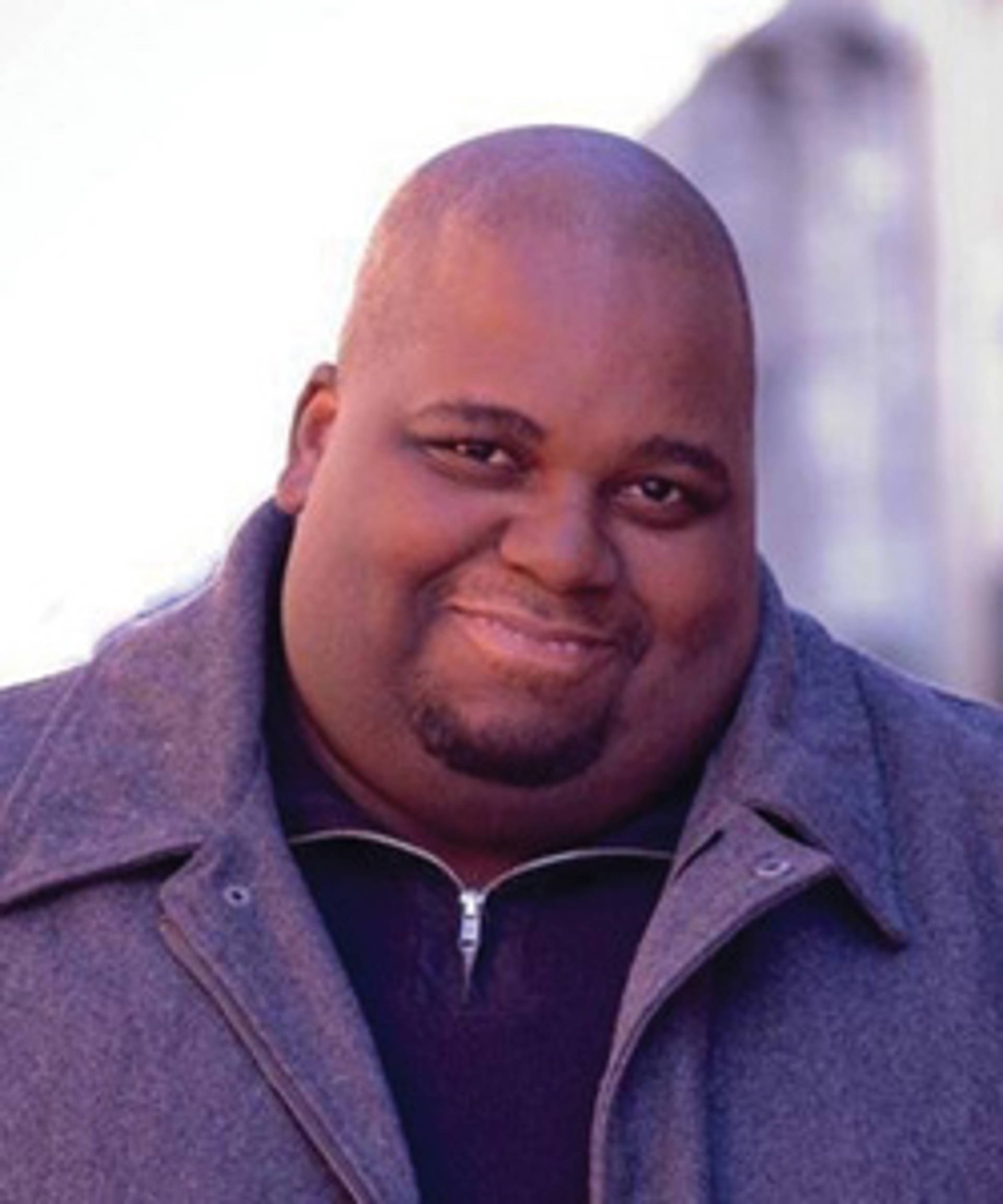 A middle aged african american man with a bald head in a coat