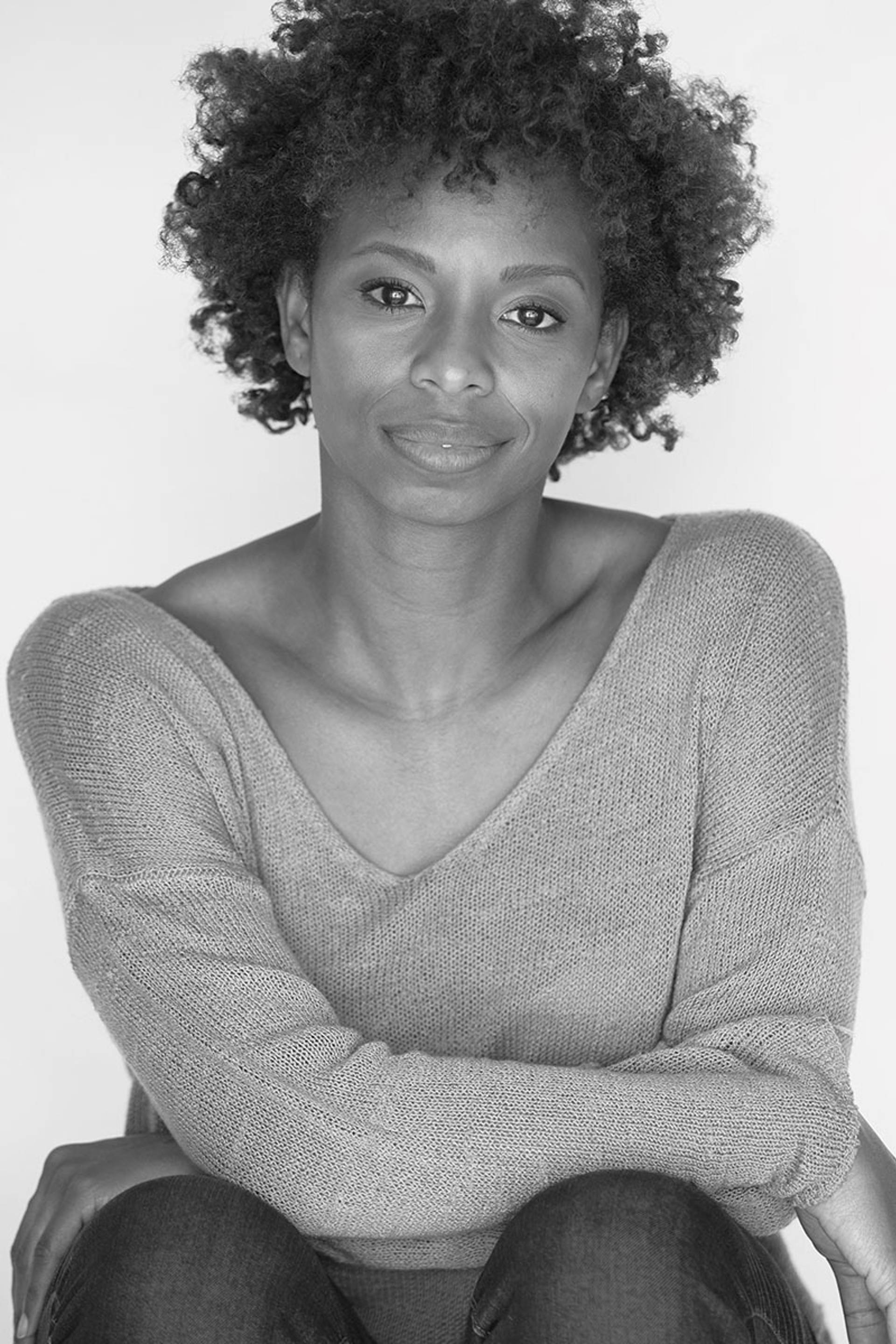 Greyscale headshot of a young african-american woman with medium curly hair and a sweater on.