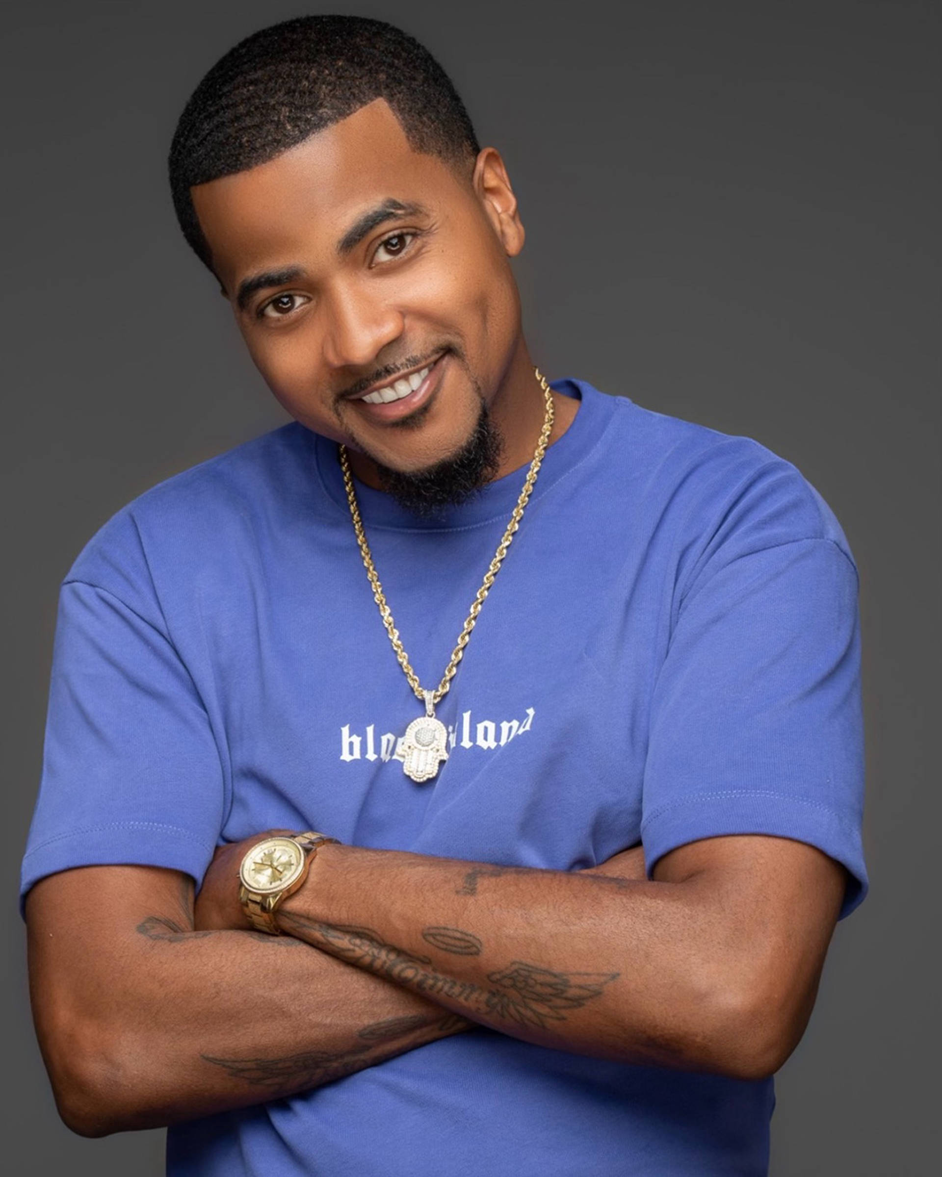 Headshot of a young african american man with short dark hair, brown eyes, and a goatee. He is wearing a blue shirt and crossing his arms.