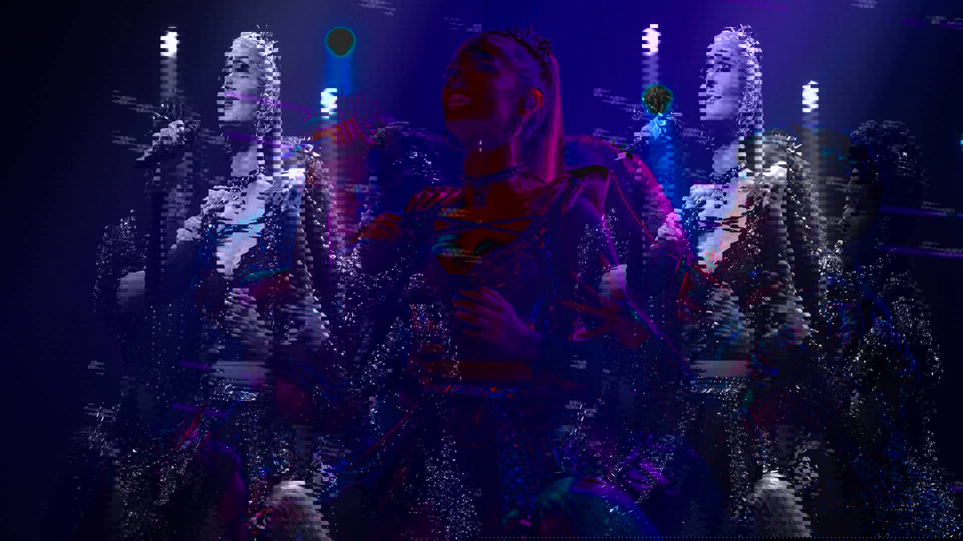 An woman in futuristic glittery outfits and holding a microphone, performing on stage