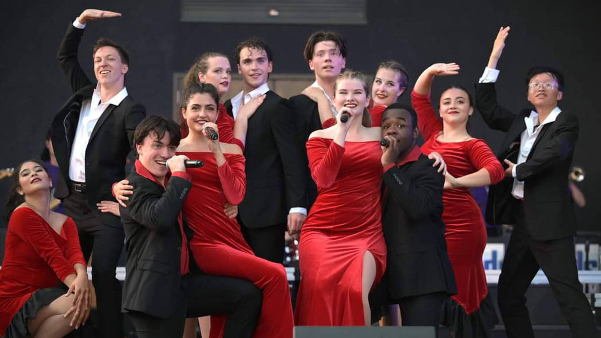 Kids from Wisconsin performing on stage. Some are in red dresses and some are in black suits with red or white dress shirts.