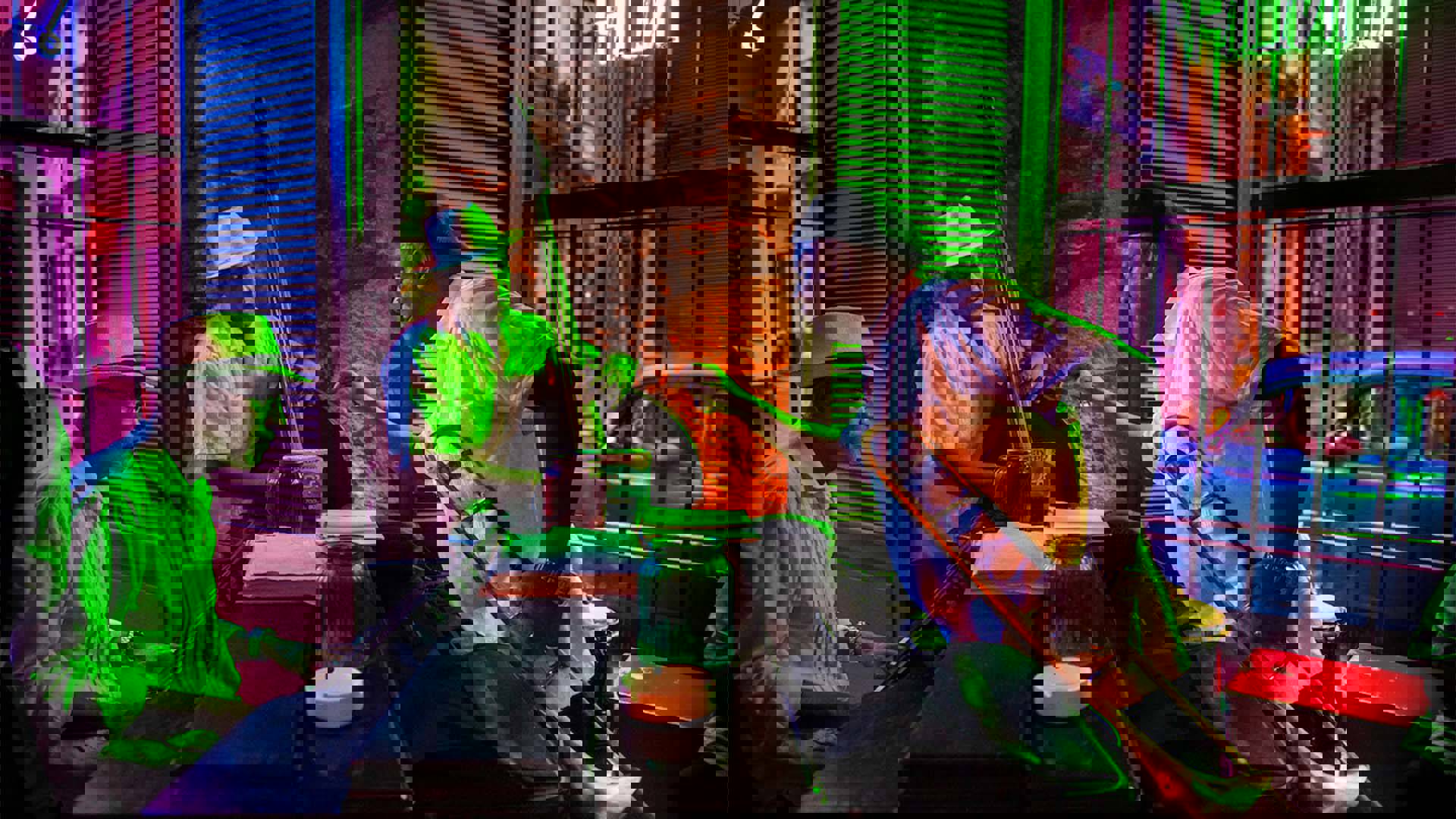 Three dark-skinned men playing music in a jazz club with neon lights. One is playing piano, one the upright bass and the other has a trombone.