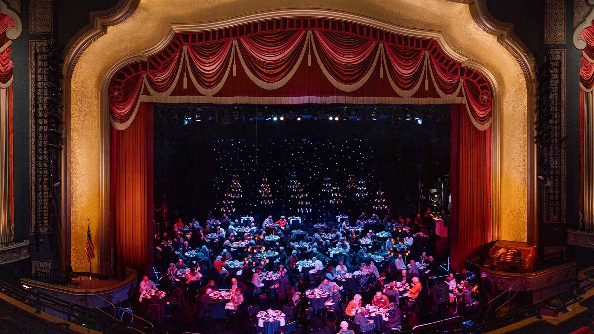The Capitol Theater stage filled with dinner tables and elegant lights hanging above.