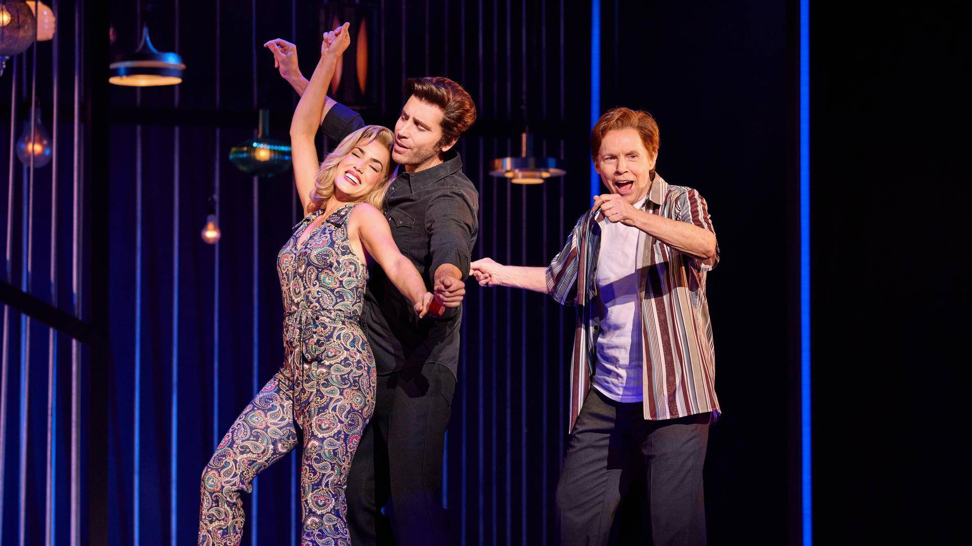 Three people dancing together against a dark background.