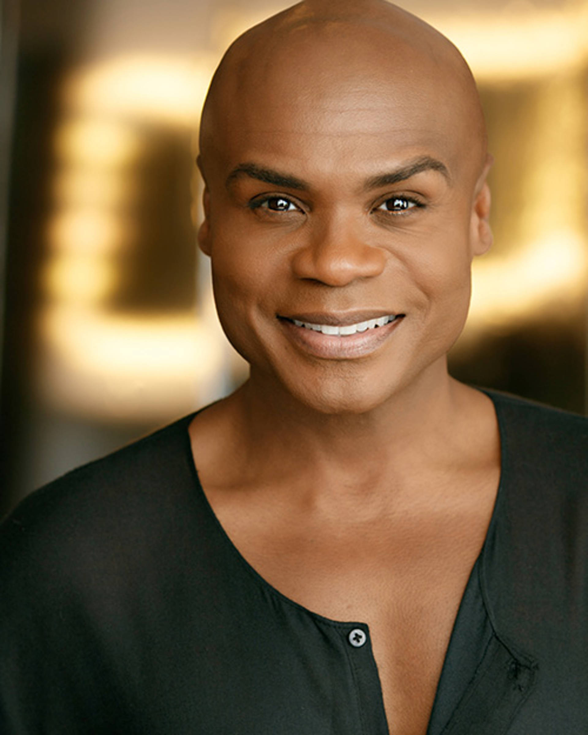 Headshot of an African American man with a bald head and brown eyes.