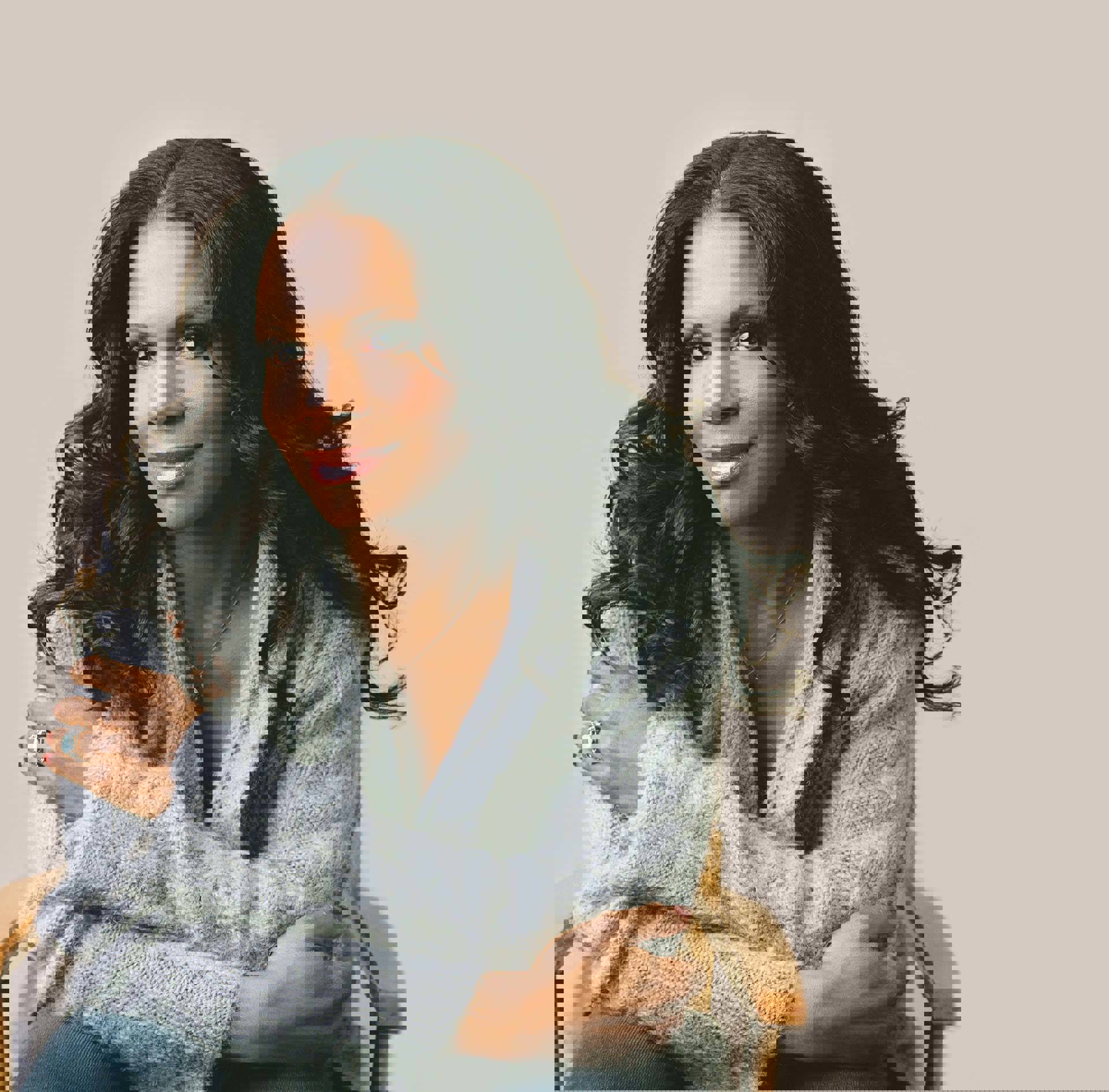 Audra McDonald, a woman with dark brown hair and a dark complexion, sits in a wooden chair wearing a grey sweater.