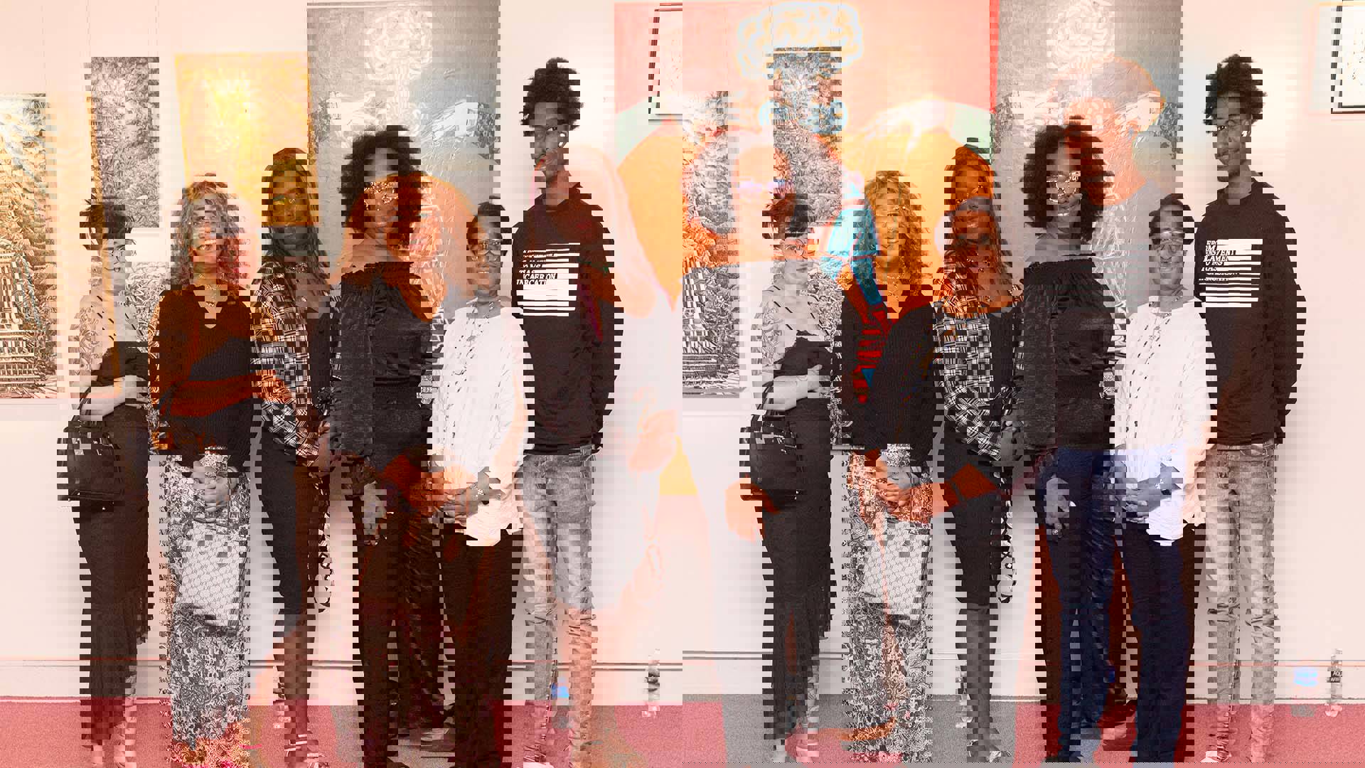 6 people stand in front of several pieces of art.