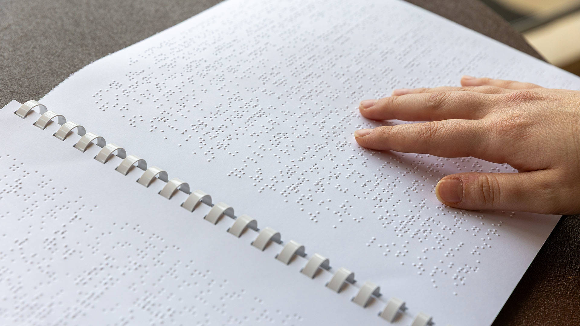 A hand touches a braille program.