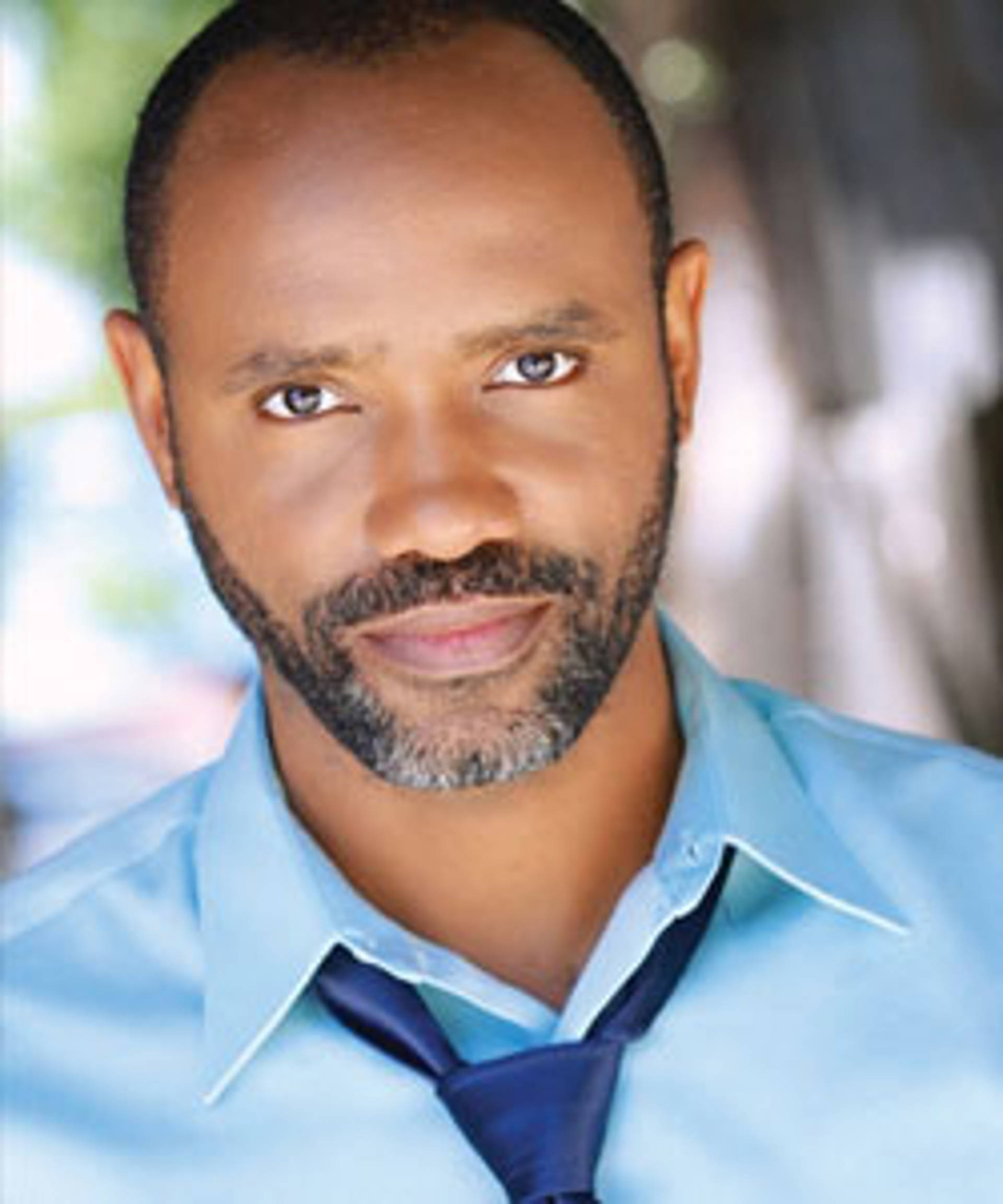 Headshot of an African American man with dark eyes and a short salt and pepper beard