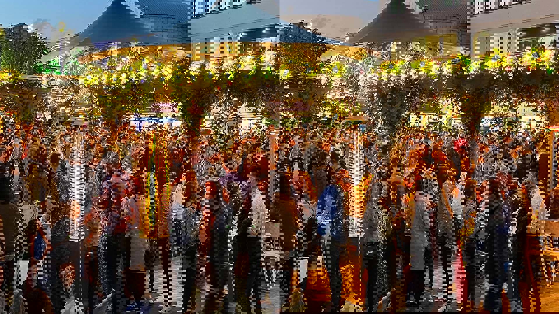 A packed outdoor party with beautiful flowery decorations.