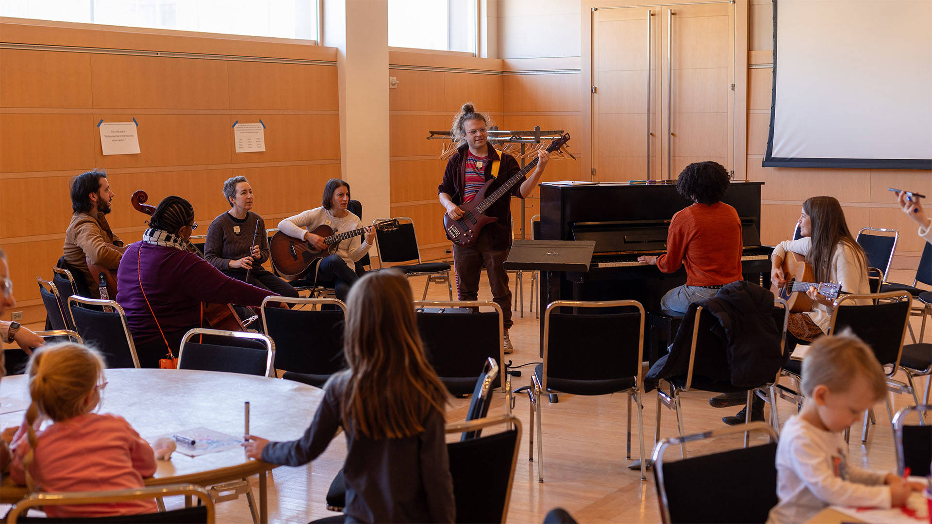 A group of musicians with various instruments playing in a seated circle.