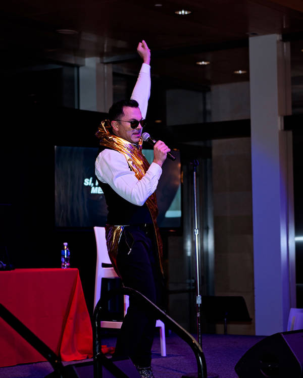 A man with  a microphone dancing with this arm up in the air.